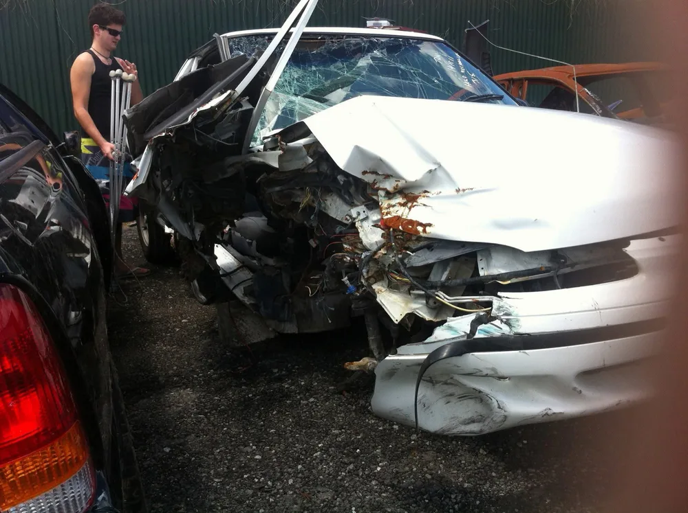 Todd beside the car after his accident, on crutches